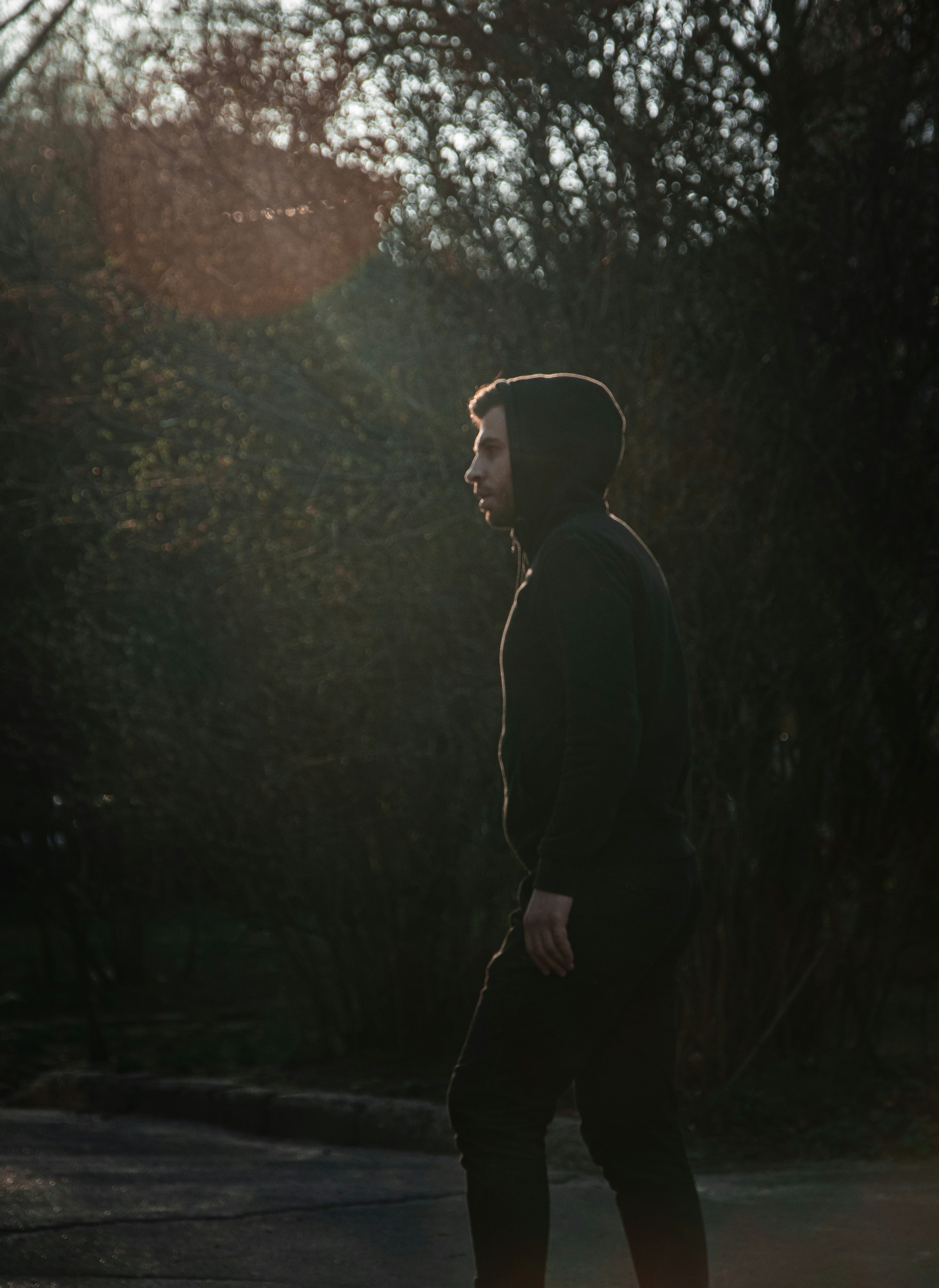 man in black jacket standing near green trees during daytime